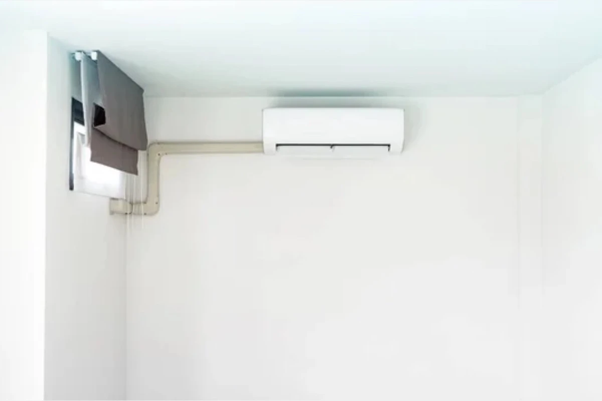 A mini split with its refrigerant and drain pipes running exposed on an interior wall.